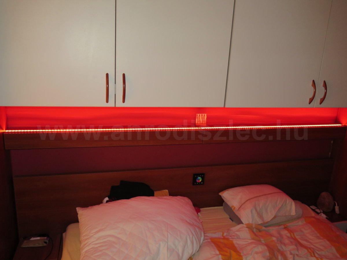 Hálószobai ágy felé szerelt RGB LED szalag, bútorlapba süllyesztett vezérlővel - így akár fekve is szabályozhatjuk a fényt.
