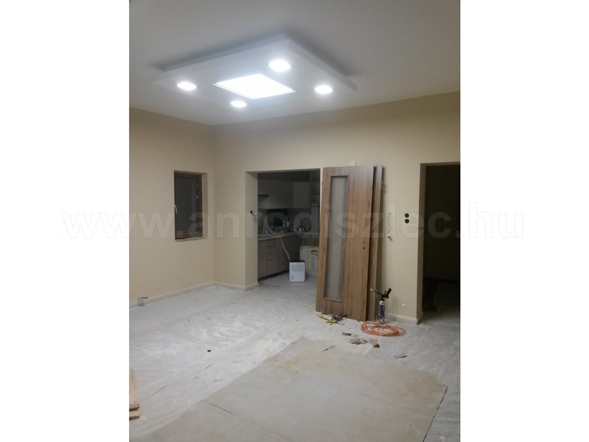 Középen egy nagy LED panel, szélén kisebb LED panelek egy álmennyezetszigetben. 