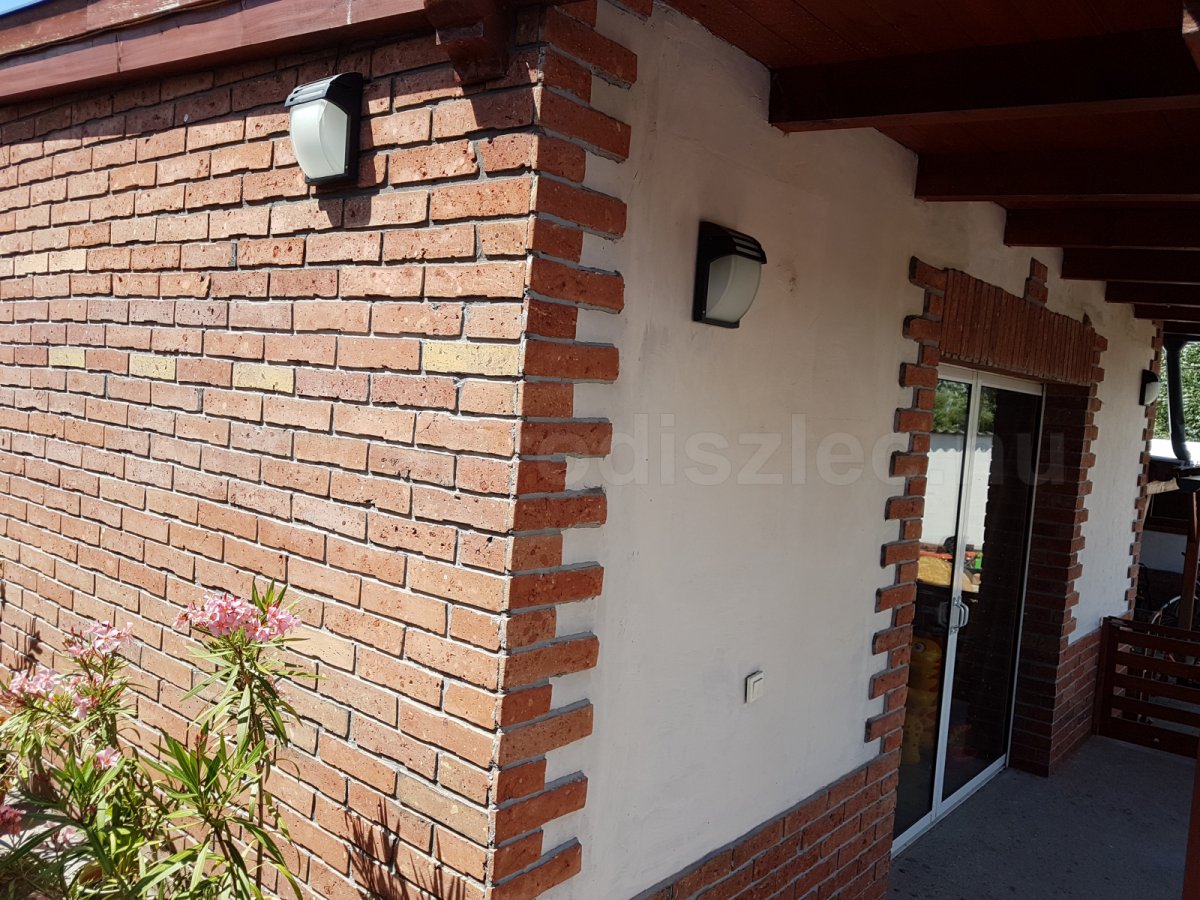 Téglával burkolat homlokzatfal fekete lámpával